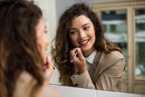 Woman smiling while applying makeup