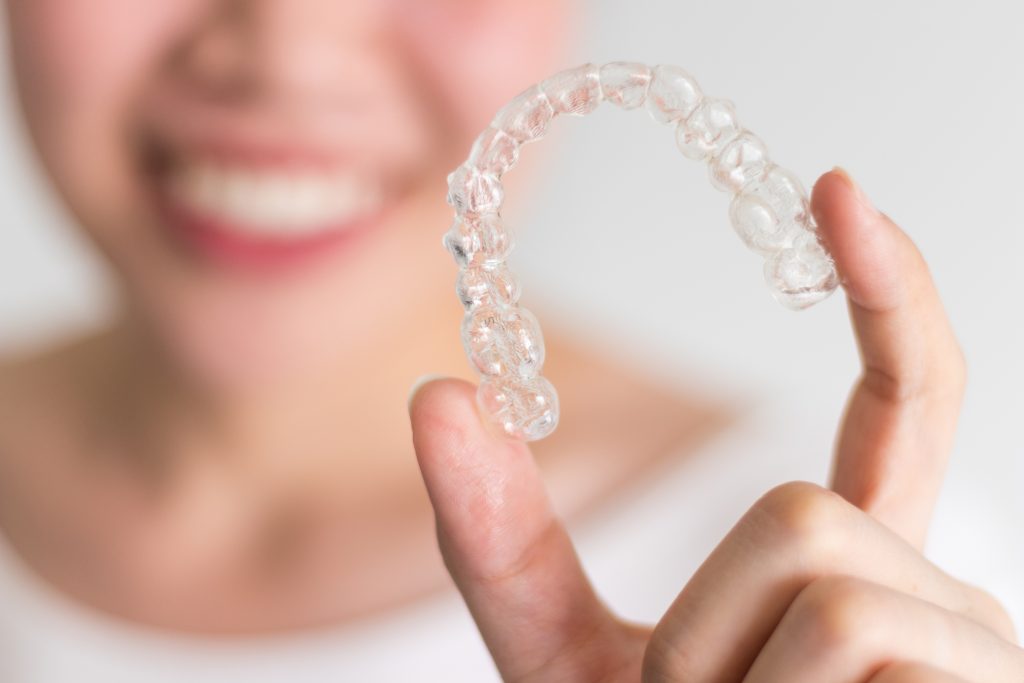 woman holding up Invisalign aligners